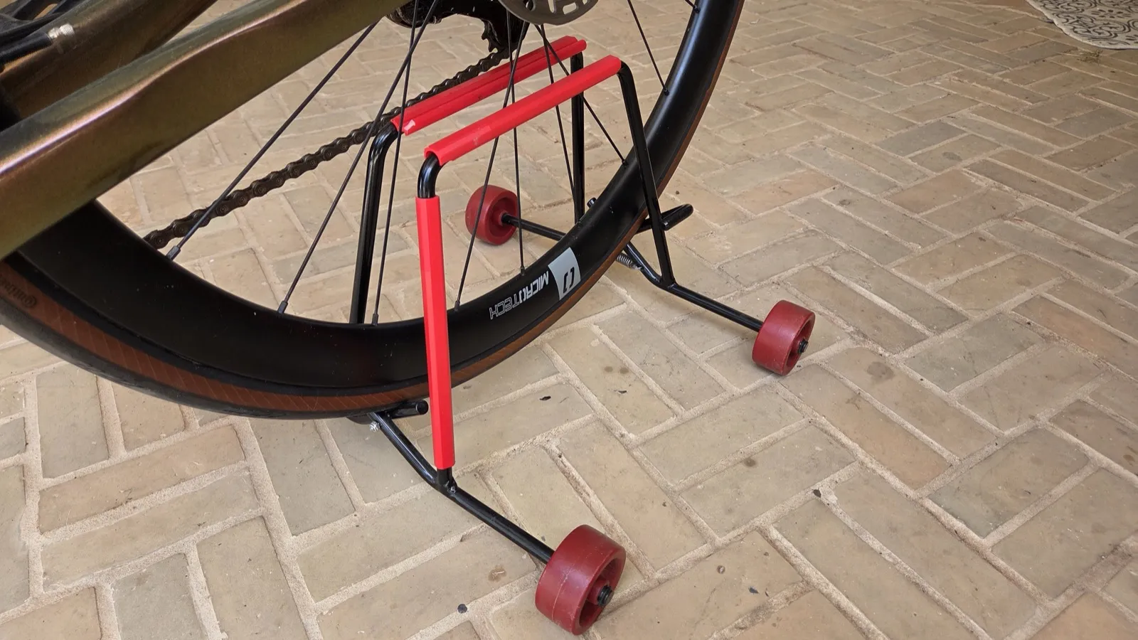The Velaris stand holding a bike outside on brick paving.